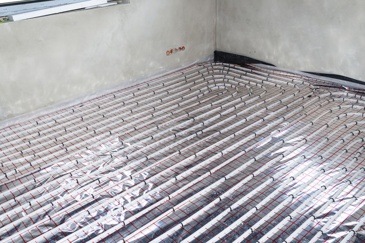 White pipes of underfloor heating systems, distributed in an individual family house on foil.
