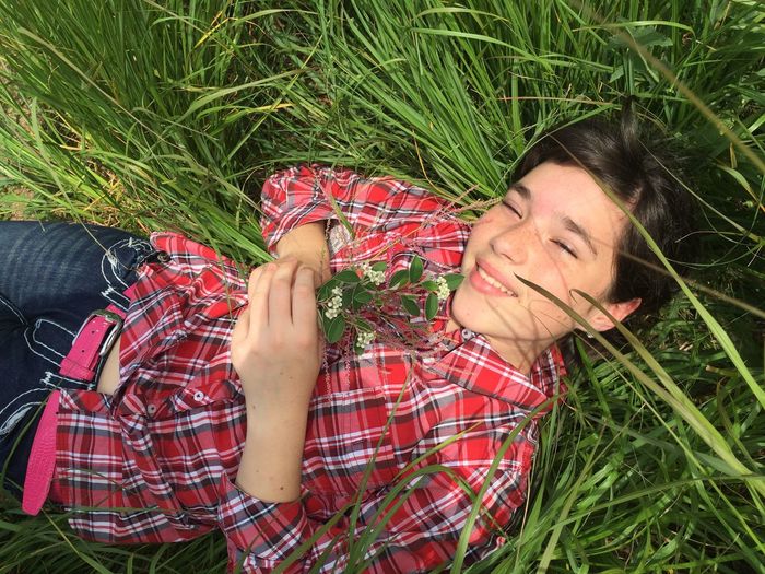 High angle view of happy girl lying on grassy field