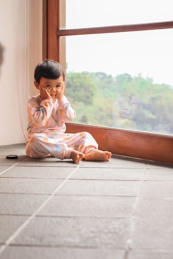 Full length of girl sitting on floor at home