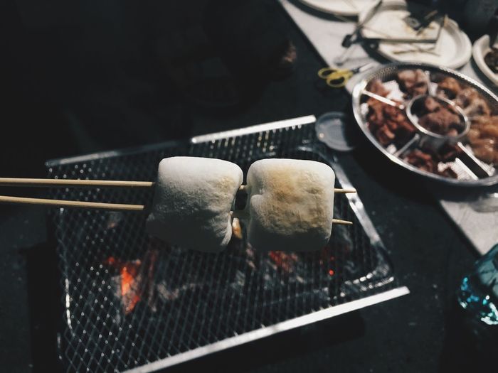 High angle view of marshmallows being cooked on barbecue grill at market stall