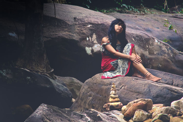 Thoughtful woman sitting on rock