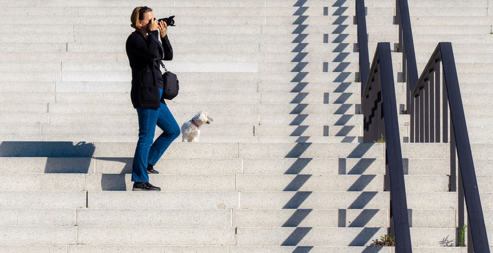 Full length of woman photographing while standing on steps