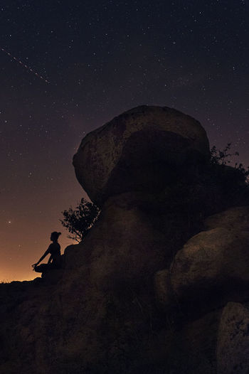 Man on rock against sky at night