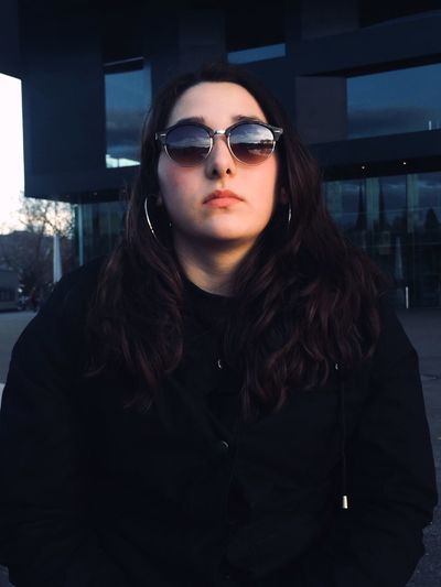 Young woman wearing sunglasses against building