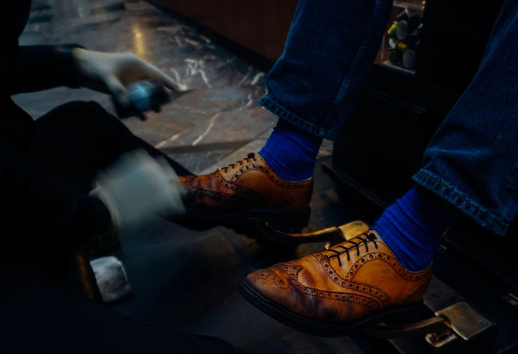 Blurred motion of shoeshiner polishing shoes of male customer