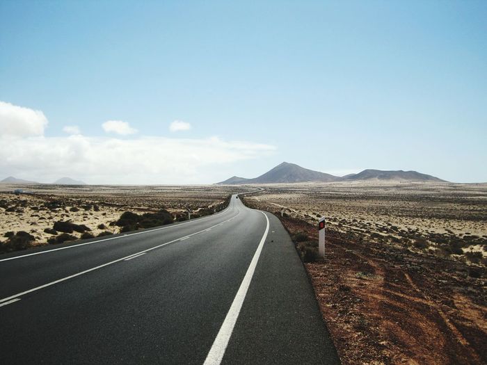 Diminishing perspective of road leading towards mountains against sky