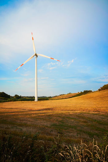 A wind turbine in field between hills in italy