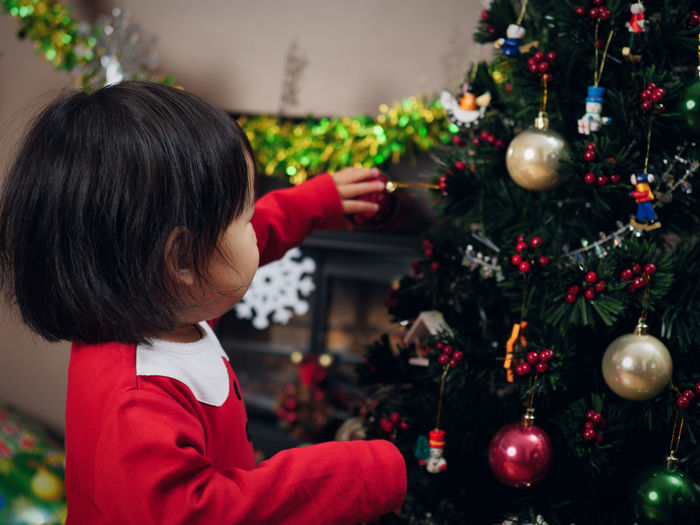 Cute girl wearing costume standing by christmas tree at home