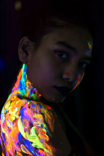 Portrait of young woman with body paint in darkroom