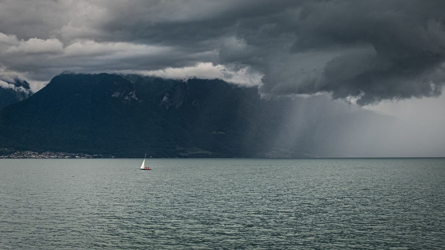 View of sailing boat on lake with heavy rain approaching