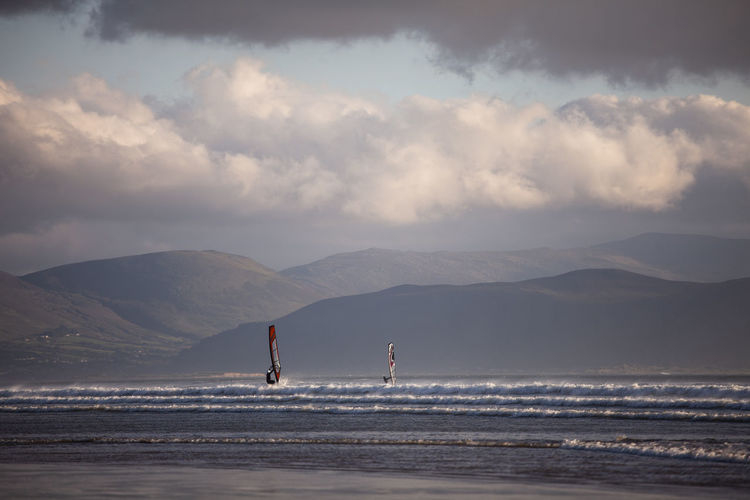 Windsurfing on beach against sky