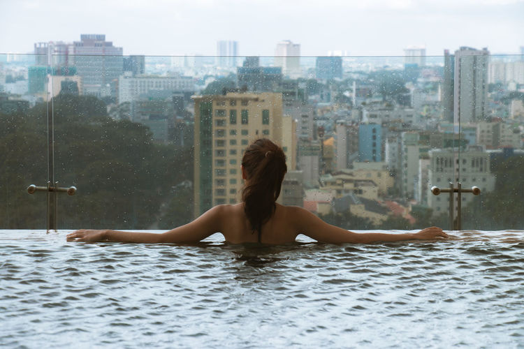 Rear view of woman swimming in infinity pool