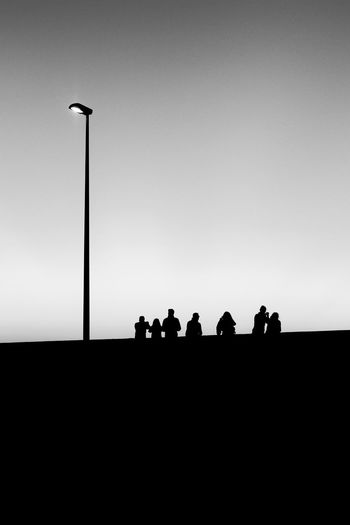 Silhouette people standing on street against clear sky