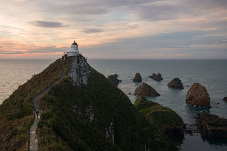 Scenic view of sea against sky during sunset with lighthouse in nugget point, new zealand.