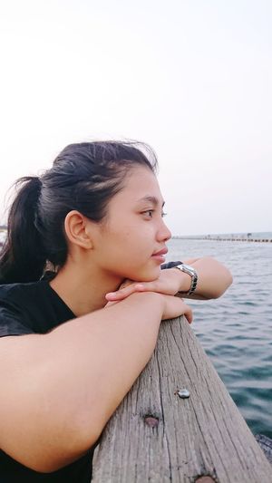 Side view of young woman looking at pier against sky