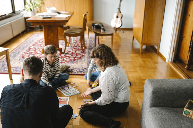 Parents joining pieces of jigsaw puzzle with children in living room