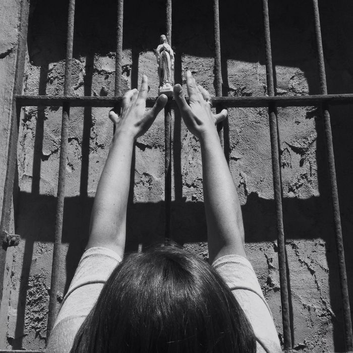 Woman praying before prison bars