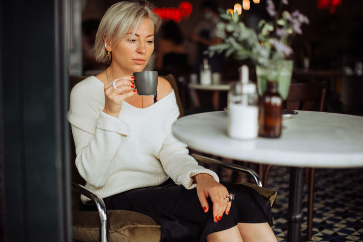 Woman holding coffee while sitting on table