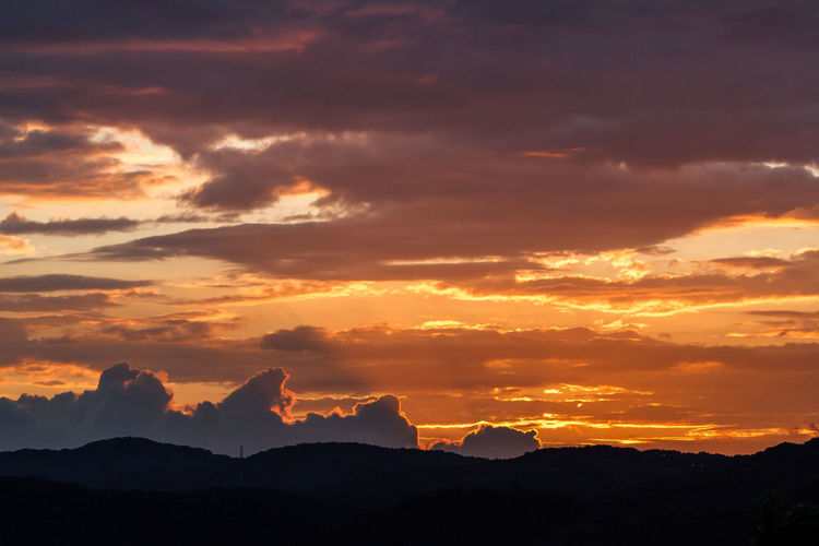 Idyllic shot of silhouette mountains against orange cloudy sky during sunset