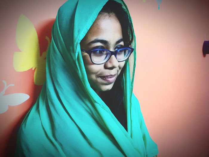 Close-up of young woman wearing green dupatta by wall