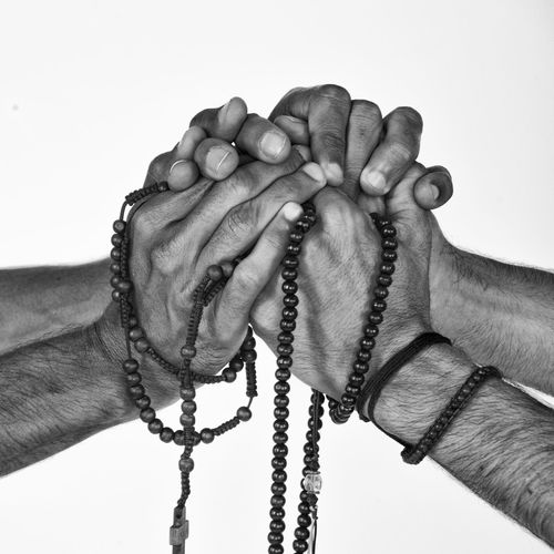 Close-up of hand holding cross against white background