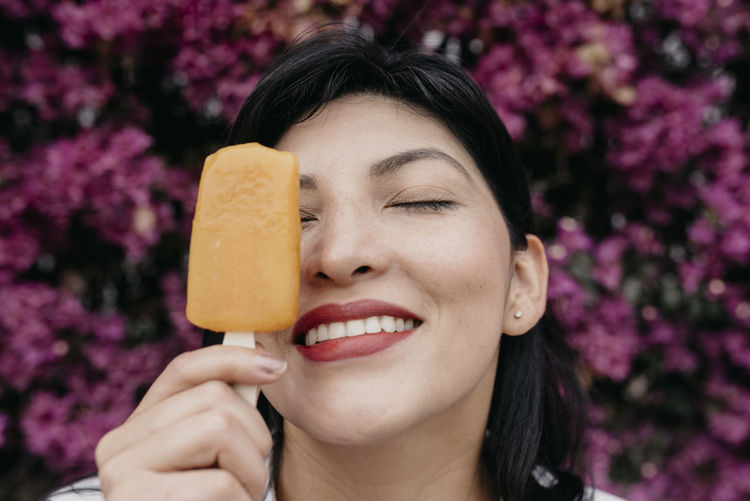 Close-up portrait of smiling woman holding ice cream
