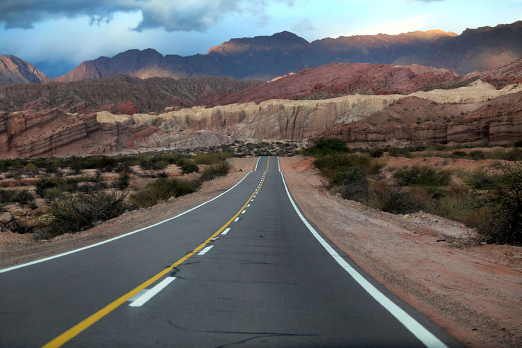 Empty road amidst mountains against sky