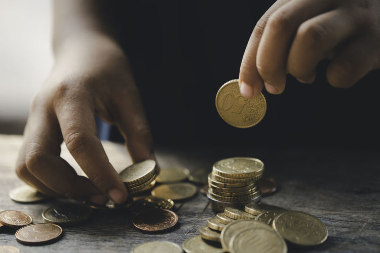 Close-up of hand holding coins over table