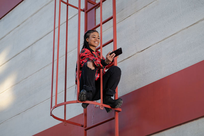 Smiling girl with african braids on a red metal ladder