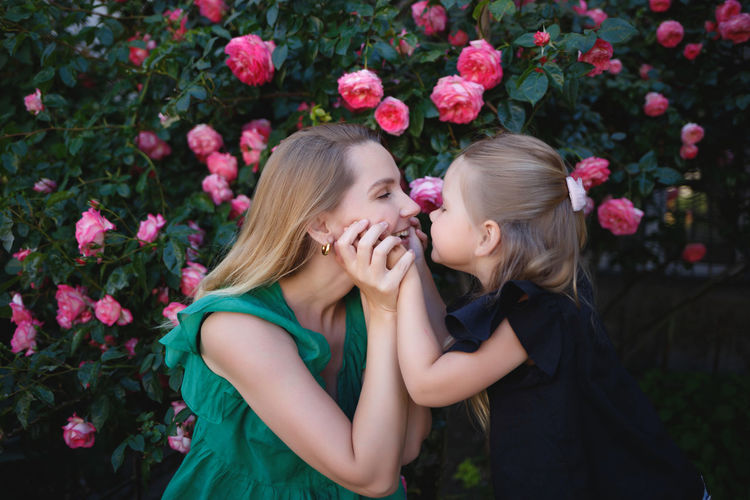 Low angle view of mother and girl amidst flowering plants