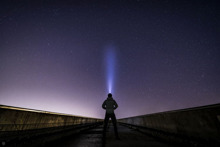 Man standing on bridge against sky at night