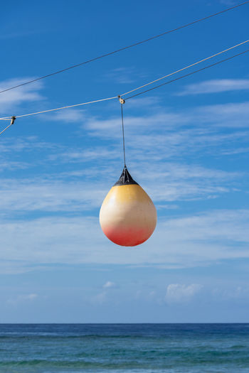 Plastic buoy hanging over sea against sky