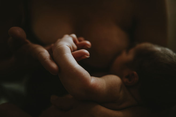 Midsection of woman breastfeeding newborn son at home