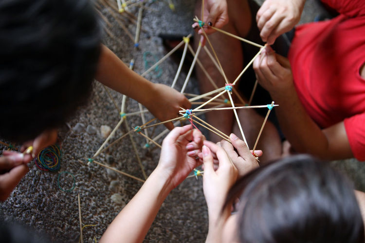 High angle view of friends making model with rubber bands and sticks