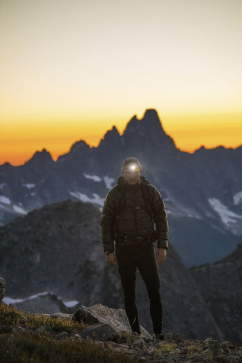 Backpacker hikes with headlamp on at dusk.