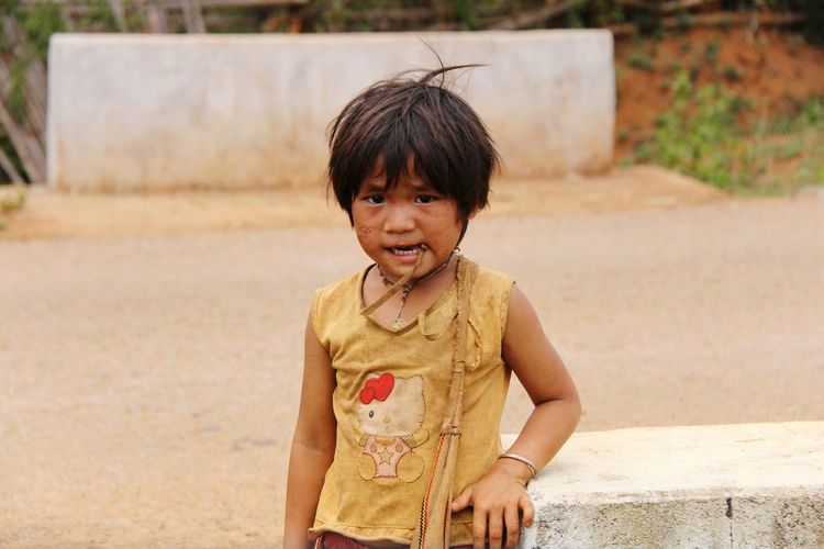 Portrait of poor girl standing on road