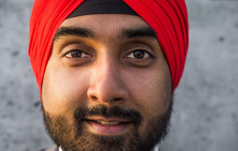 Close-up portrait of businessman wearing turban standing against wall
