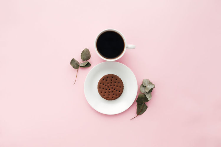 Woman international day concept, coffee cup, plate, cookie, branch, leaves on pink background