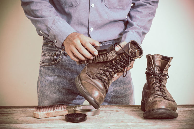 Midsection of man polishing boots