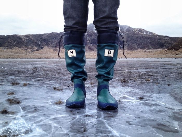 Low section of man standing on frozen lake
