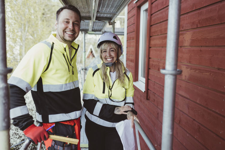 Cheerful male and female colleague standing together at scaffolding