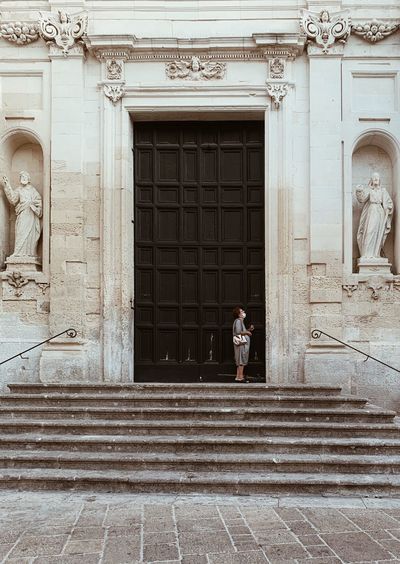 Woman standing by door of historic building