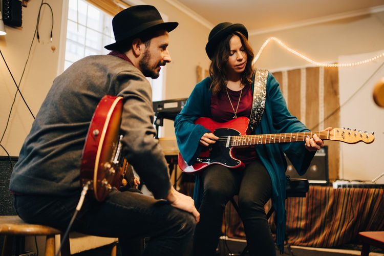 Low angle view of male and female friends playing guitars at recording studio