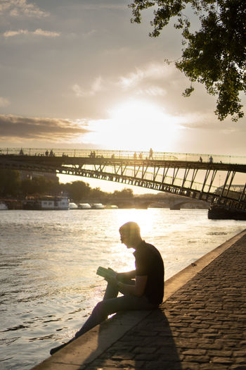 Reading a book at seine river in paris, france