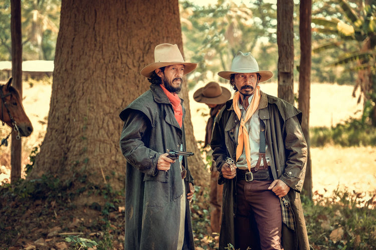 Cowboys standing in forest