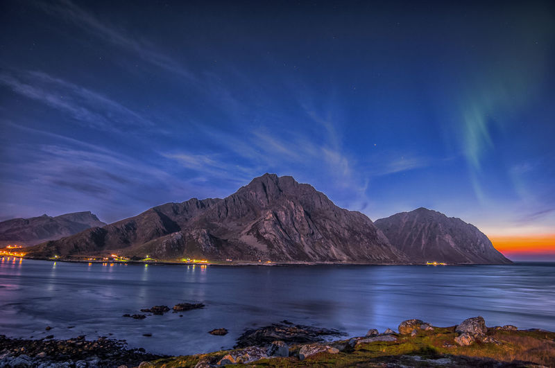 Scenic view of sea and mountains against sky at night