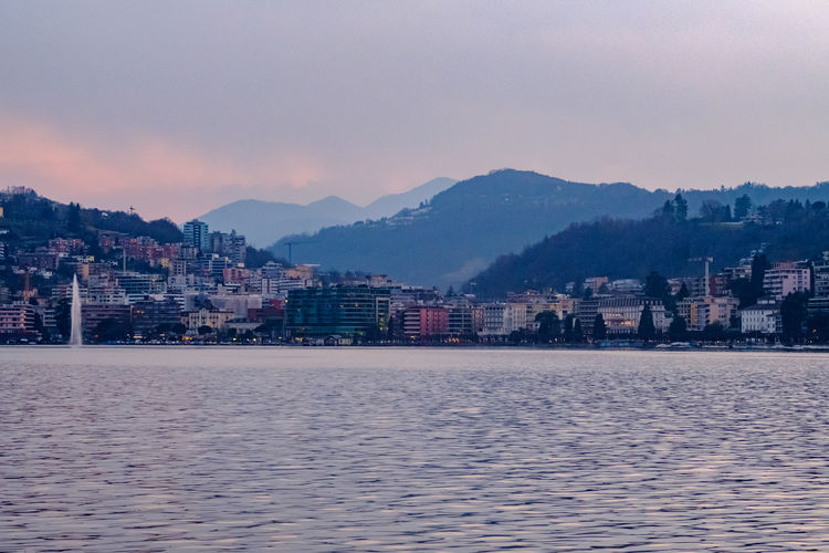 Scenic view of sea and buildings against sky at dusk