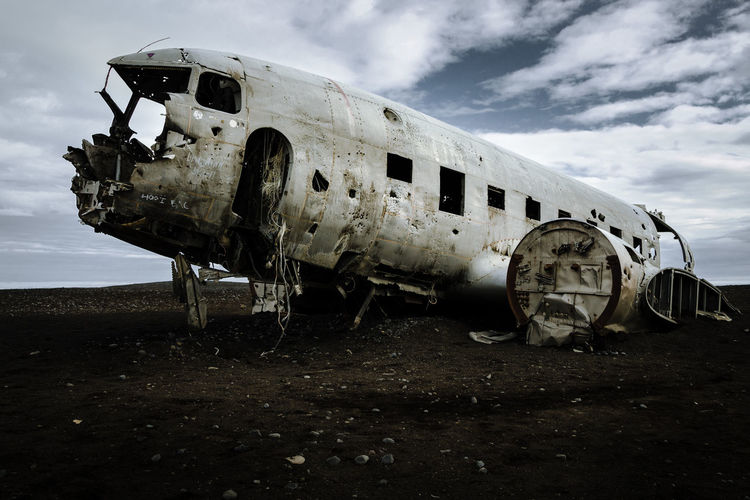 Abandoned airplane on airport runway against sky