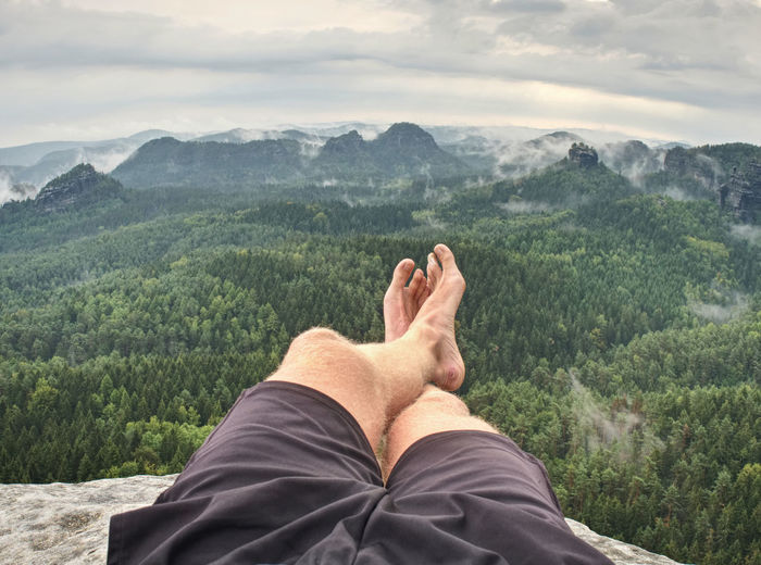 Man feet with hiking shoes on stone mountain background. spring morning in rocky mountains