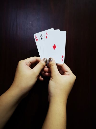Cropped hands of woman holding ace cards on table